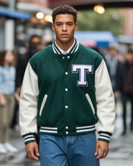 Person wearing a green and white varsity jacket with a large 'T' on a blurred street background