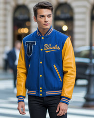 Man wearing a blue and yellow varsity jacket with 'UWales' on a city street.