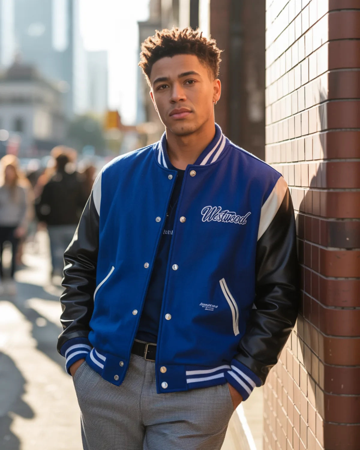 Person wearing a blue and black varsity jacket leaning against a brick wall.